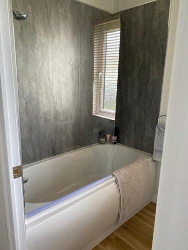 a white bath tub in a bathroom with a window at Morwenna Lodge in Bude