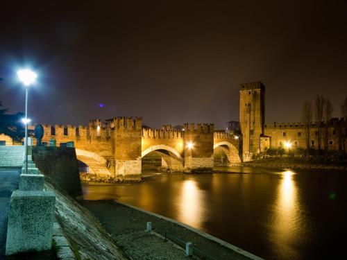 a castle at night with a bridge over the water at Arena Verona Centro in Verona