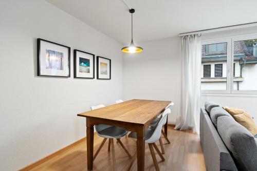 a dining room with a wooden table and a couch at Bright, Central & Modern apartment in Luzern