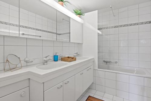 a white bathroom with a sink and a tub at Bright, Central & Modern apartment in Luzern