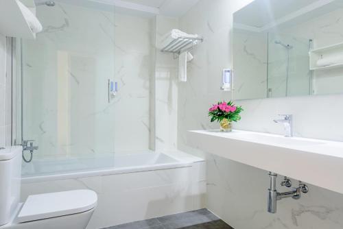 a white bathroom with a sink and a toilet and a tub at BS Principe Felipe in Albolote