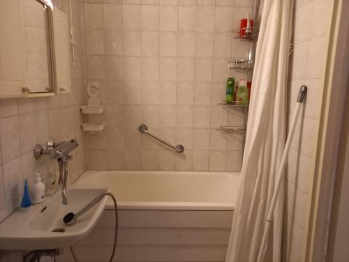 La salle de bains est pourvue d'une baignoire, d'un lavabo et d'une douche. dans l'établissement Kaksio Pieksämäen keskustassa, à Pieksämäki