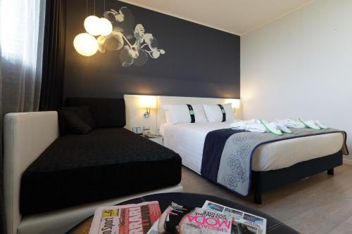 a hotel room with two beds and a couch at Holiday Inn Milan Nord Zara by IHG in Cinisello Balsamo