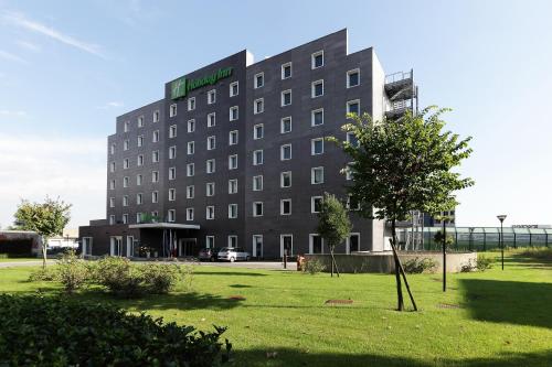 un edificio con un cartello verde sulla parte anteriore di Holiday Inn Milan Nord Zara, an IHG Hotel a Cinisello Balsamo