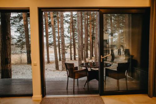 a glass door leading to a patio with a table and chairs at GaujaUpe in Gauja