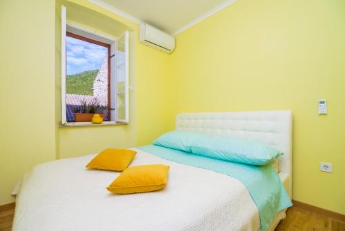 sypialnia z białym łóżkiem z żółtymi i niebieskimi poduszkami w obiekcie Villa Nives w mieście Žuljana