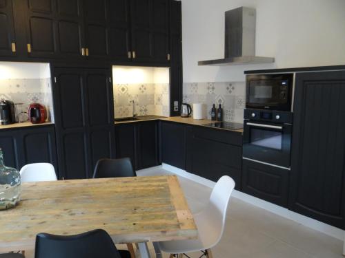 une cuisine avec des armoires noires et une table en bois dans l'établissement Au bon coin, à Sarlat-la-Canéda