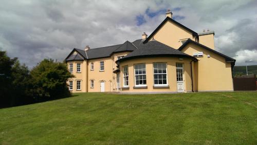 a large house on top of a grass field at Emlagh House in Dingle
