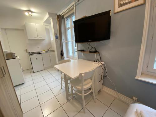 eine Küche mit einem Tisch und einem TV an der Wand in der Unterkunft Joli Studio proche plage et centre avec parking in Wimereux