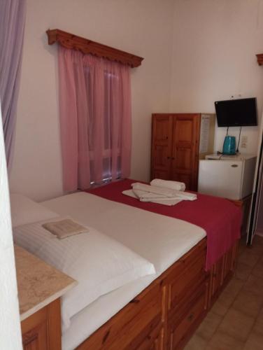 a bedroom with two beds and a window with a tv at Pagali Hotel in Órmos Aiyialís