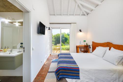 a bedroom with a bed and a sink and a mirror at Abacatus Farmhouse in Tavira