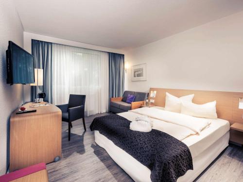 ein Hotelzimmer mit einem großen Bett und einem Schreibtisch in der Unterkunft Mercure Hotel Saarbrücken Süd in Saarbrücken