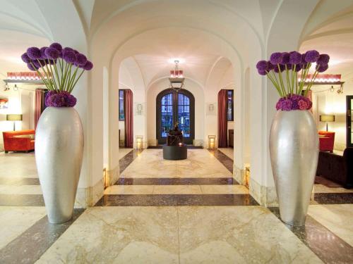 two white vases with purple flowers in a hallway at Sofitel Legend The Grand Amsterdam in Amsterdam