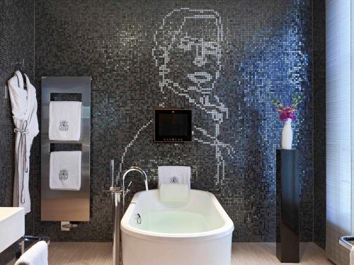 
a bathroom with a bathtub, toilet and a painting on the wall at Sofitel Legend The Grand Amsterdam in Amsterdam
