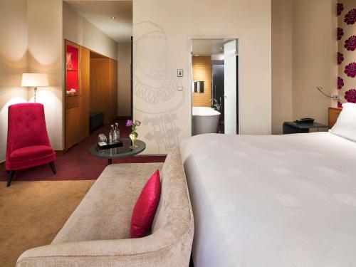a hotel room with a large bed and a red chair at Sofitel Legend The Grand Amsterdam in Amsterdam