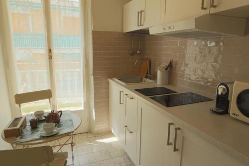 een keuken met witte kasten, een wastafel en een raam bij La Piccola Florida in Sanremo