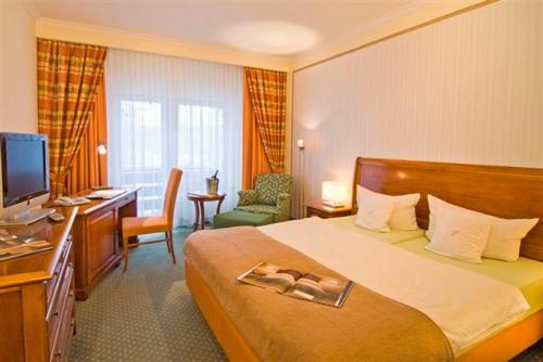 コリーンにあるSeehotel Mühlenhausのベッド、デスク、テレビが備わるホテルルームです。