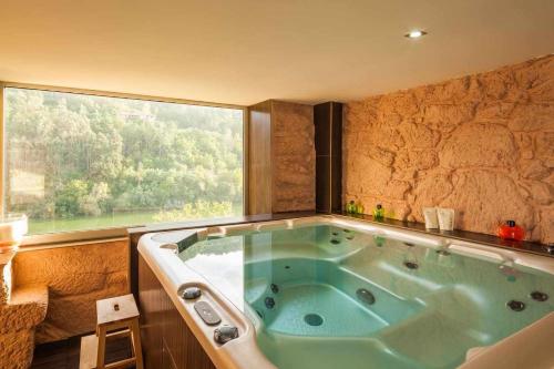 a bath tub in a room with a large window at Vila Spa Douro Piscina e acesso privado rio Douro in São Lourenço do Douro