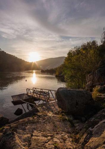 a bench on the shore of a river with the sunset at Vila Spa Douro Piscina e acesso privado rio Douro in São Lourenço do Douro