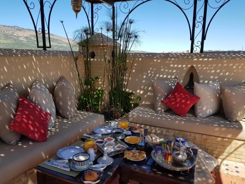 Riad Fes Kettani في فاس: طاولة مليئة بالطعام على أريكة مع الوسائد