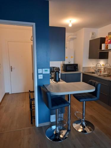 une cuisine avec une table et deux tabourets de bar dans l'établissement magnifique appartement 3 étoiles centre ville et mer à pied, à Saint-Brévin-les-Pins