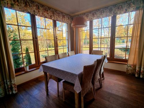 een eetkamer met een tafel, stoelen en ramen bij Zacisze Jurajskie in Olsztyn