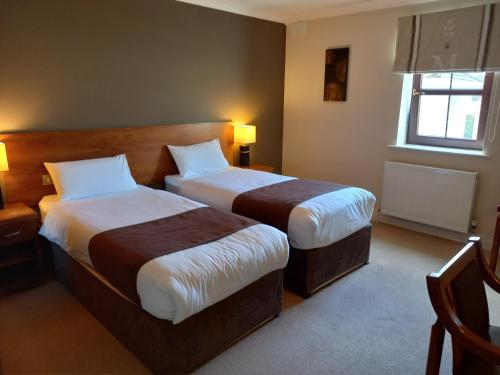 a hotel room with two beds and a window at Hillcrest Guest House in Clonmel