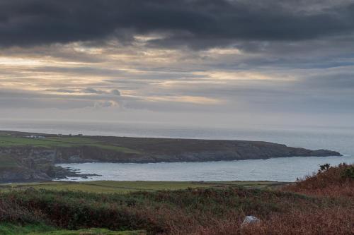 uma vista para o oceano a partir de uma colina com o céu em Tan Y Cytiau em Holyhead