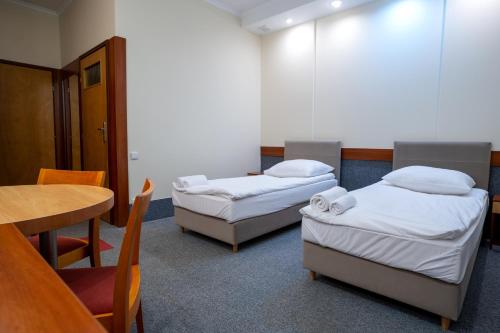 a room with two beds and a table and a table and chairs at Hotel Lord Gorlice in Gorlice