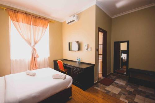 sypialnia z łóżkiem, biurkiem i oknem w obiekcie Panone Hotel Boma w mieście Boma la Ngombe