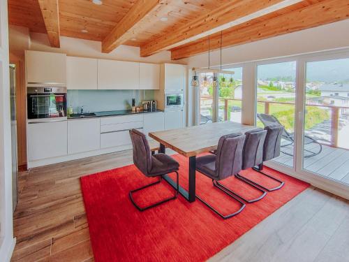 eine Küche mit einem Holztisch und Stühlen auf einem roten Teppich in der Unterkunft Downhill Lodge Tauplitz in Tauplitz