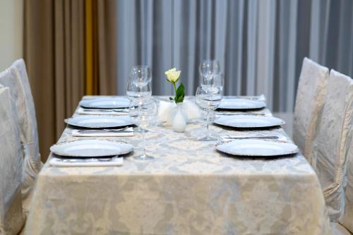 a table with plates and glasses and a flower on it at Hotel Lord Gorlice in Gorlice