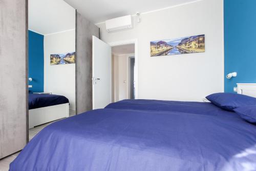 a bedroom with a blue bed and a mirror at DADA 2bd App - nuovo in CENTRO zona Navigli in Milan