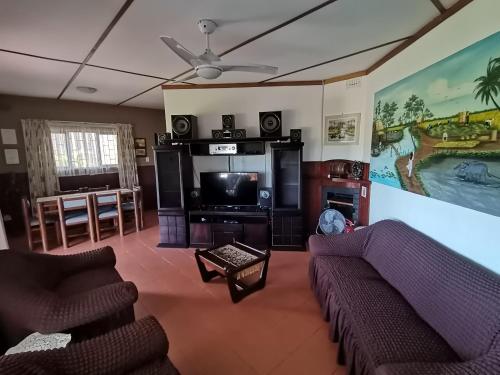 Il comprend un salon avec des canapés et une télévision à écran plat. dans l'établissement Ridgeview Holiday Accommodation, à Umzumbe