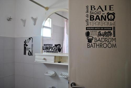 a bathroom with a shower door with words on the wall at Ruca Kiñe Hostel in Las Grutas