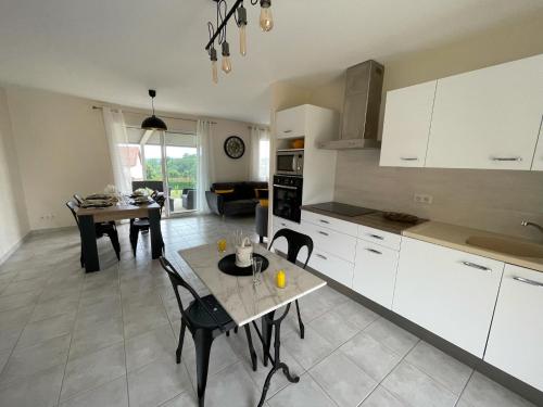 une cuisine avec des armoires blanches et une table avec des chaises dans l'établissement Les Jardins de Maelle, à Belvès