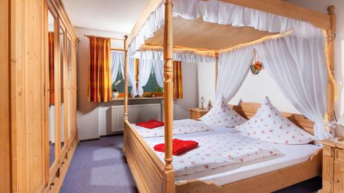 a bedroom with a canopy bed with red pillows at Ferienwohnung Steinlehen in Marktschellenberg