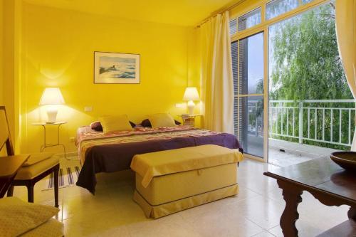 a yellow bedroom with a bed and a balcony at VCV Villa Magua in Santa Brígida