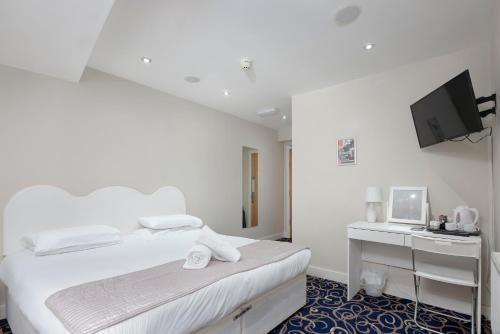 a white bedroom with a white bed and a desk at The R Inn Hotel in Desborough