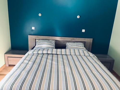 une chambre avec un lit avec un mur bleu dans l'établissement Maison de charme et accueillante, à Chalifert