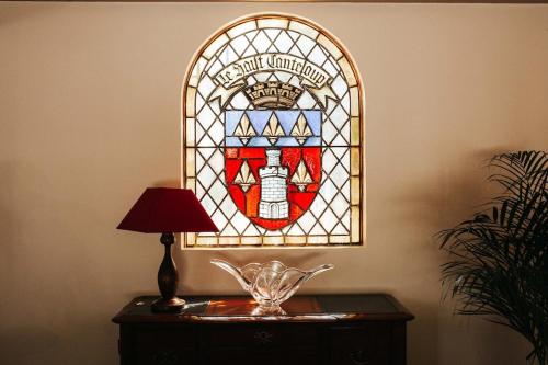 a stained glass window on a table with a lamp at Demeure du Haut Canteloup in Honfleur