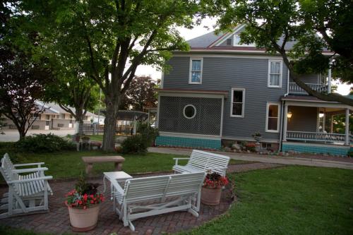 three white benches sitting in a yard in front of a house at The Shelby Inn in Shelbyville
