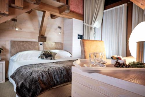 a bedroom with a large bed and a table with glasses at Hotel Belmonte in Roana