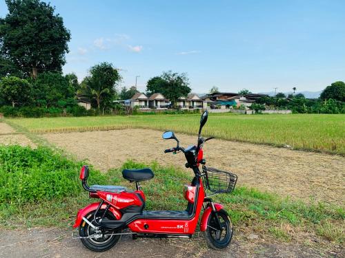 una moto roja estacionada al lado de un campo en KraThom Doi Luang, en Chiang Dao