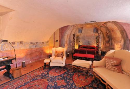 a bedroom with a bed and a couch and chairs at Château de Bagnols in Bagnols