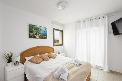 1 dormitorio blanco con 1 cama y TV en A white dream by the sea - 2bd lux family apartment en Herzliyya B