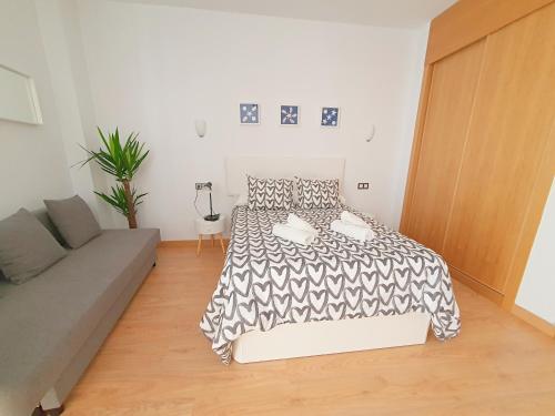 een slaapkamer met een bed en een bank erin bij Precioso Estudio con Piscina in Málaga
