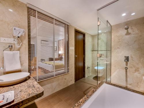 een badkamer met een bad, een wastafel en een douche bij Freesia By Express Inn in Pālghar