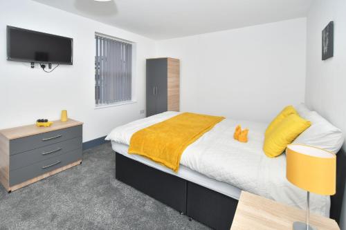 a bedroom with a large bed with a yellow blanket at Townhouse @ 24 Brunswick Place Stoke in Etruria