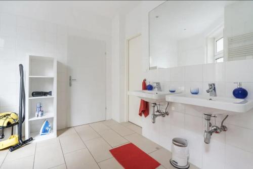a white bathroom with two sinks and a red rug at Apartment France | Operastreet in Vienna